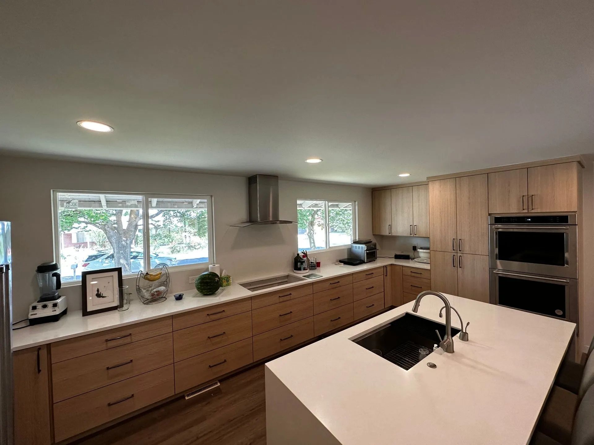 Modern kitchen with light wood cabinets, white countertops, and stainless steel appliances.