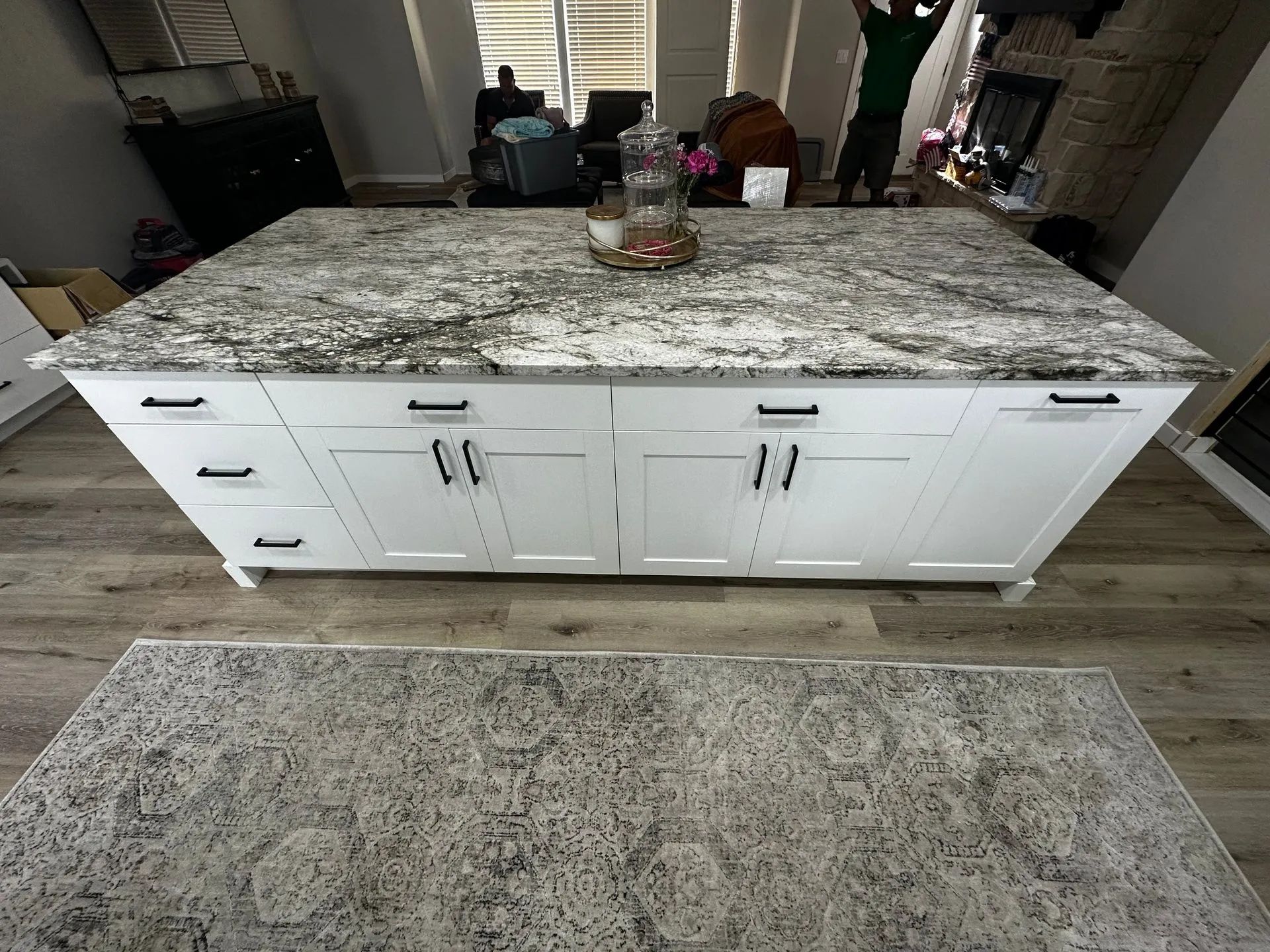 White kitchen island with granite countertop, cabinet doors, and drawers.
