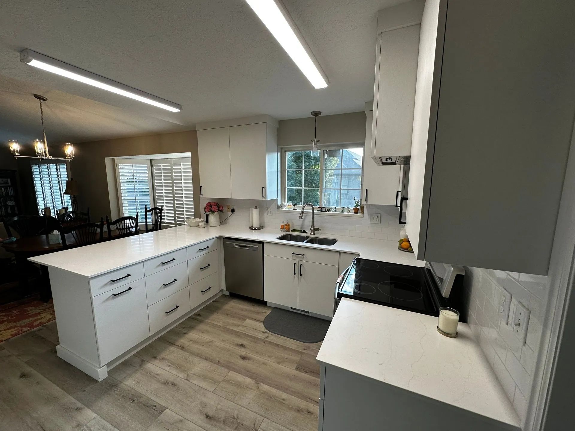 Modern white kitchen with island, stainless steel appliances, and light wood floors.