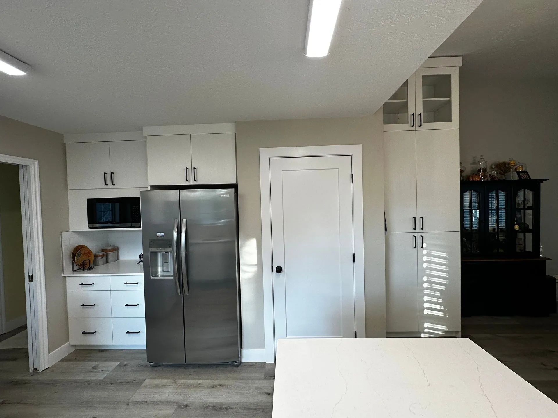 Kitchen with white cabinets, stainless steel refrigerator, and a white door.