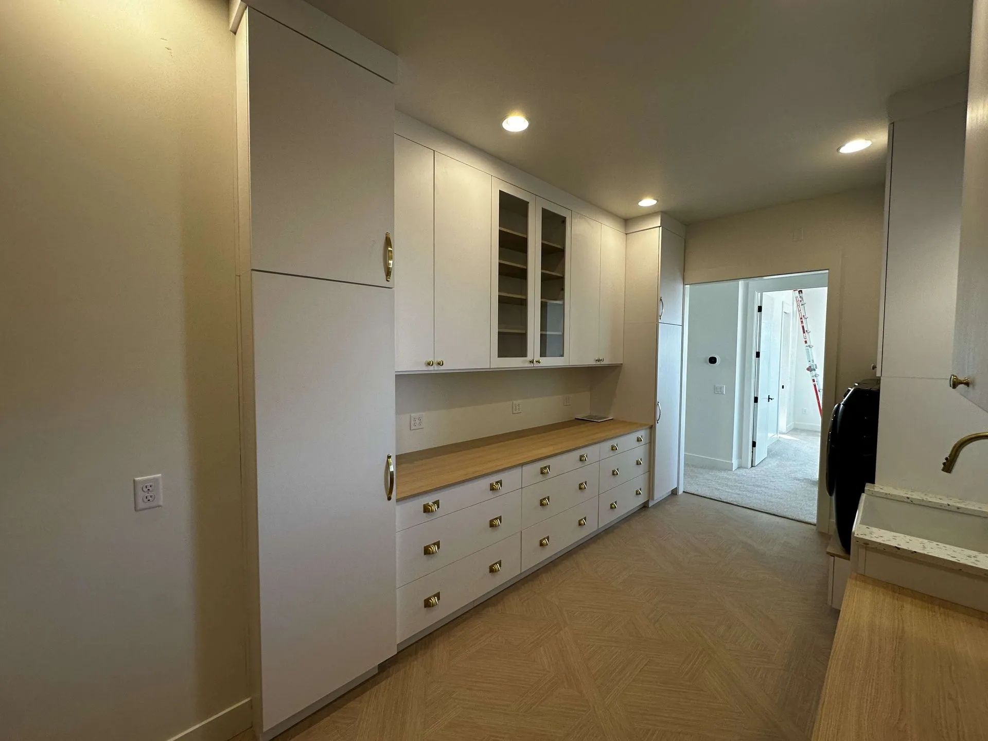A white cabinet-lined room with a long counter and a doorway. Light-colored carpet.