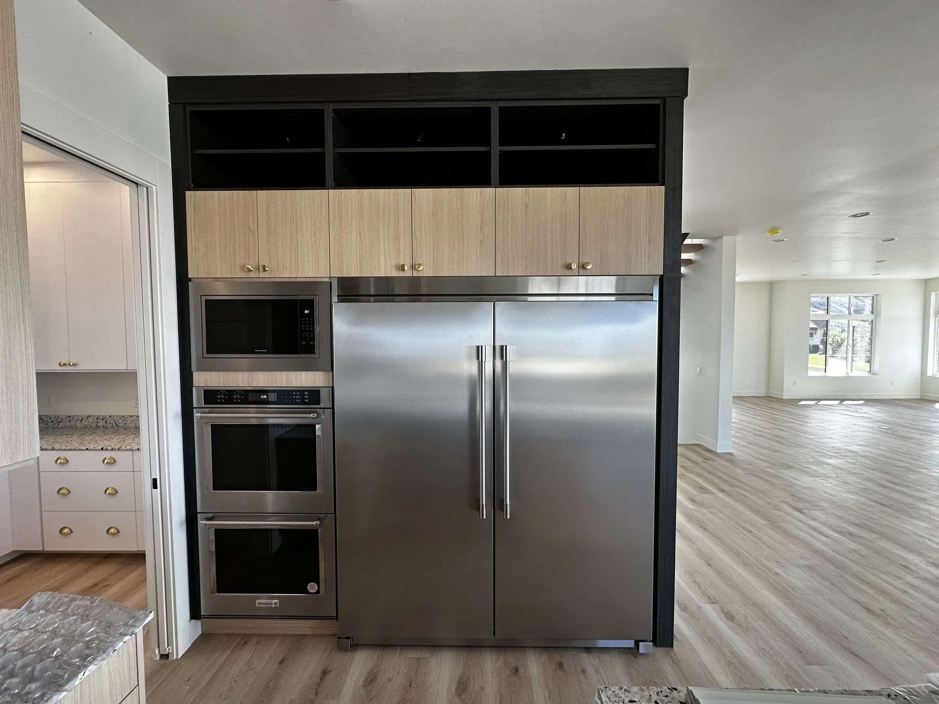 Stainless steel refrigerator, microwave, and oven built into a cabinet with overhead storage.