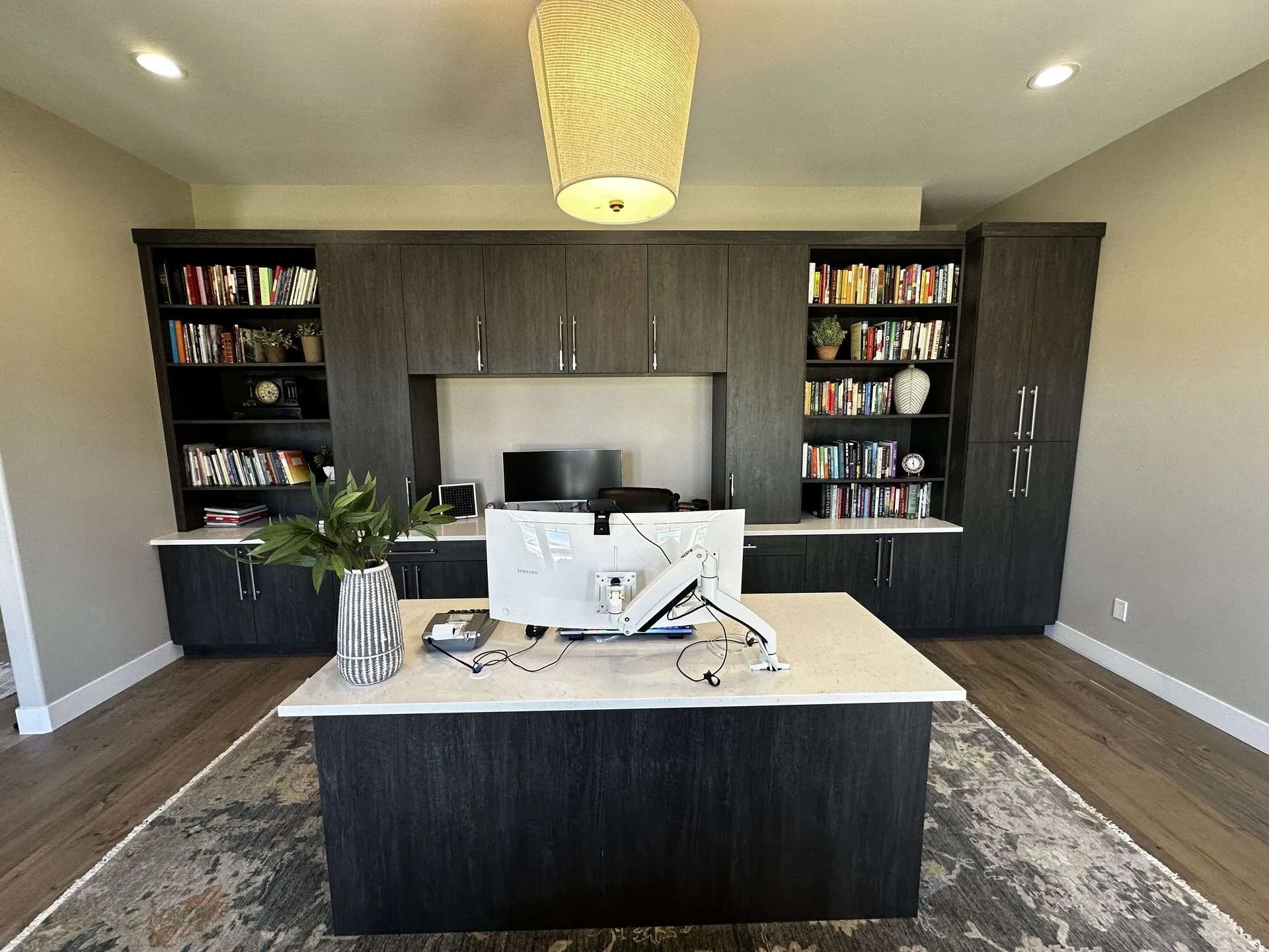 Home office with a large desk, built-in shelving, and a patterned rug.