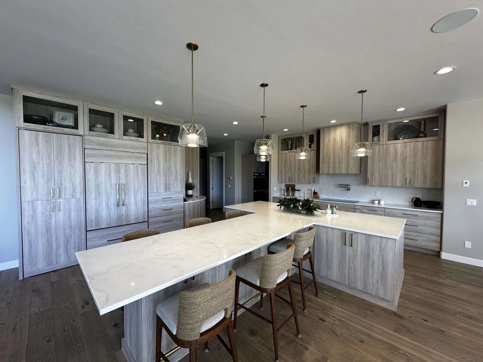 Modern kitchen with light wood cabinets, white countertops, and bar seating.