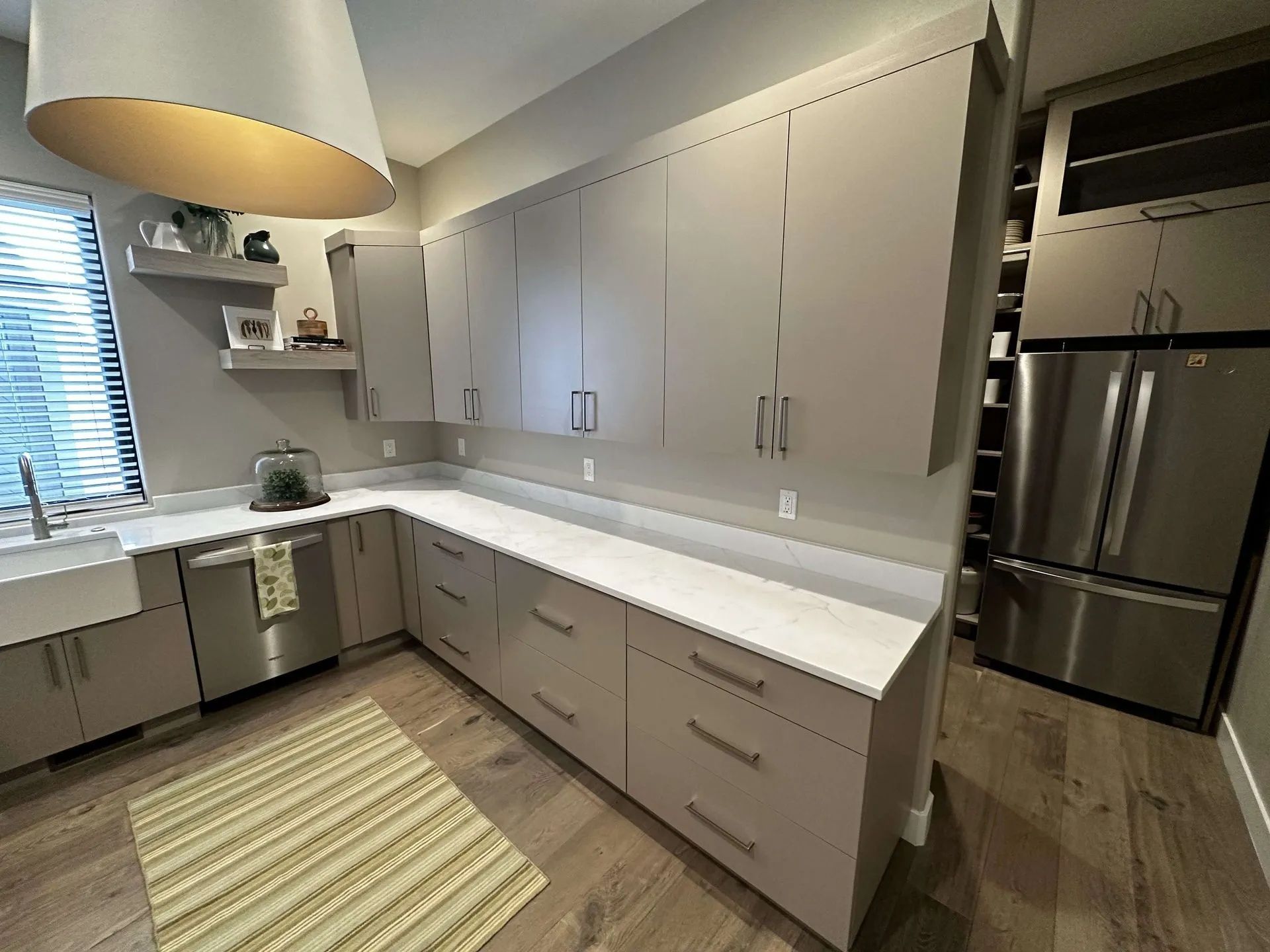 Modern kitchen with gray cabinets, white countertops, and stainless steel appliances.