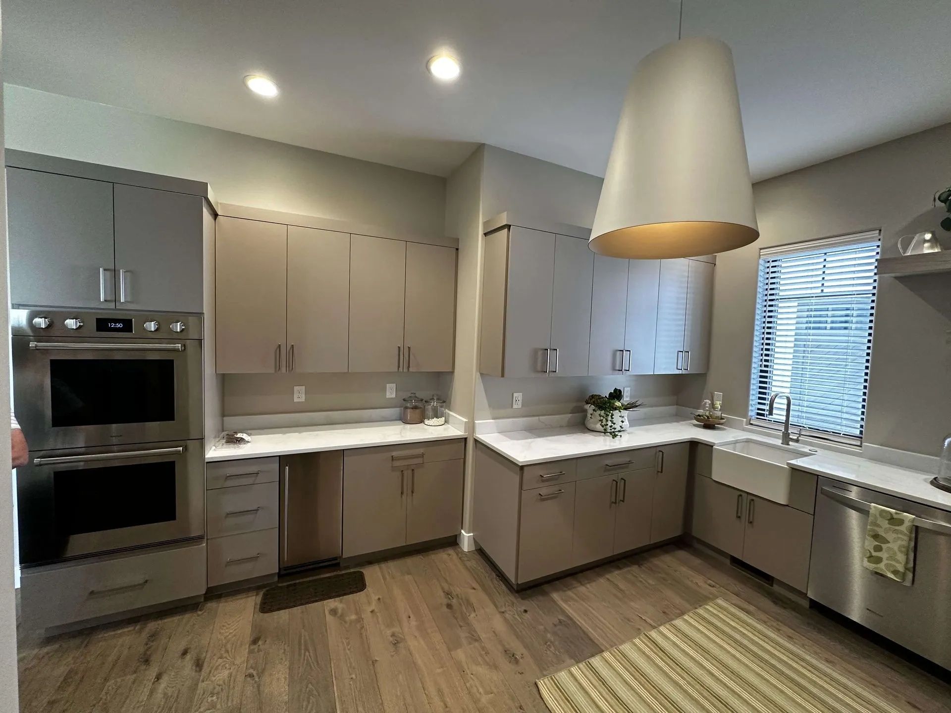 Modern kitchen with light gray cabinets, stainless steel appliances, and wood floors.