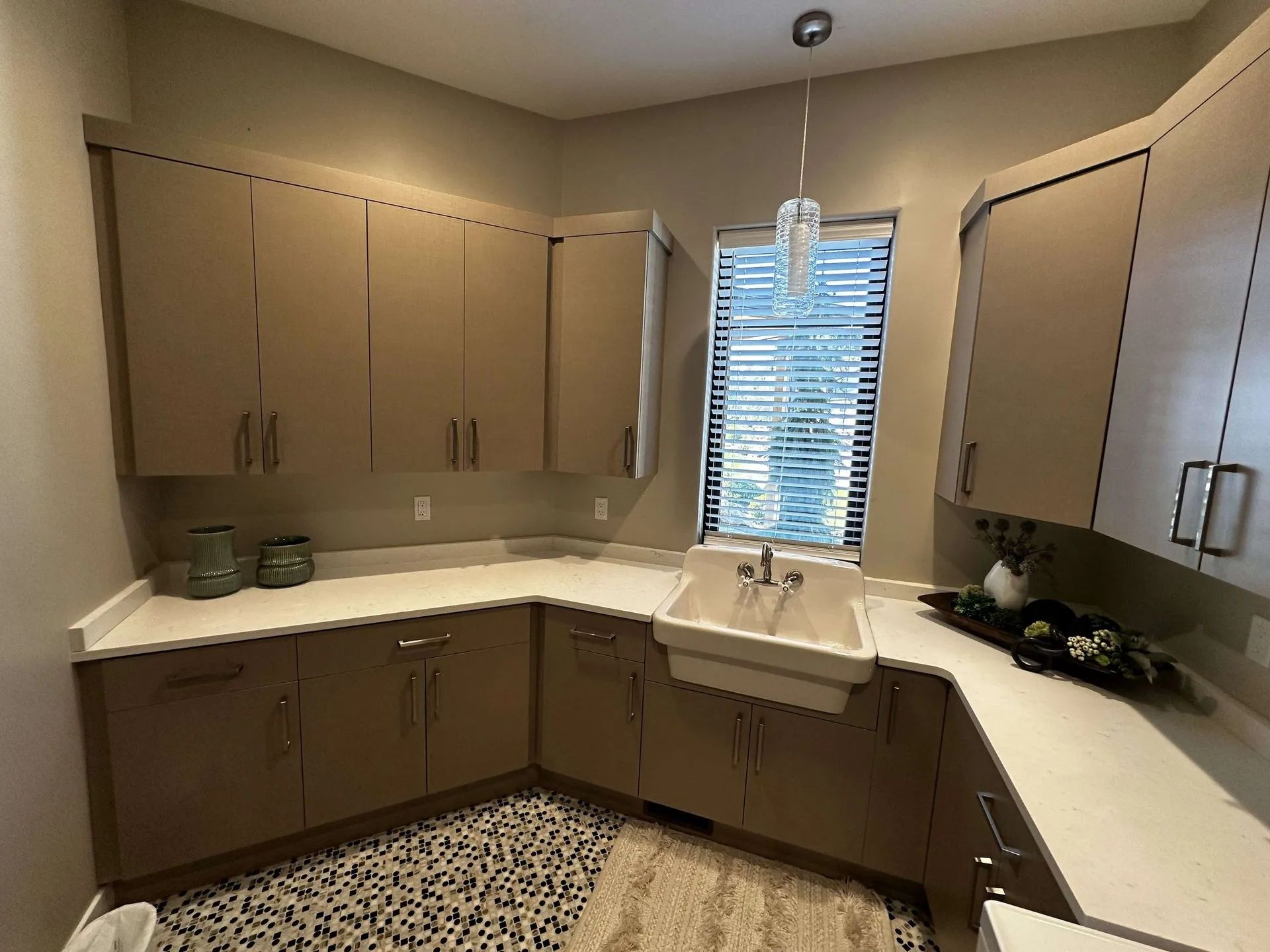 Laundry room with tan cabinets, white countertops, and a white sink.