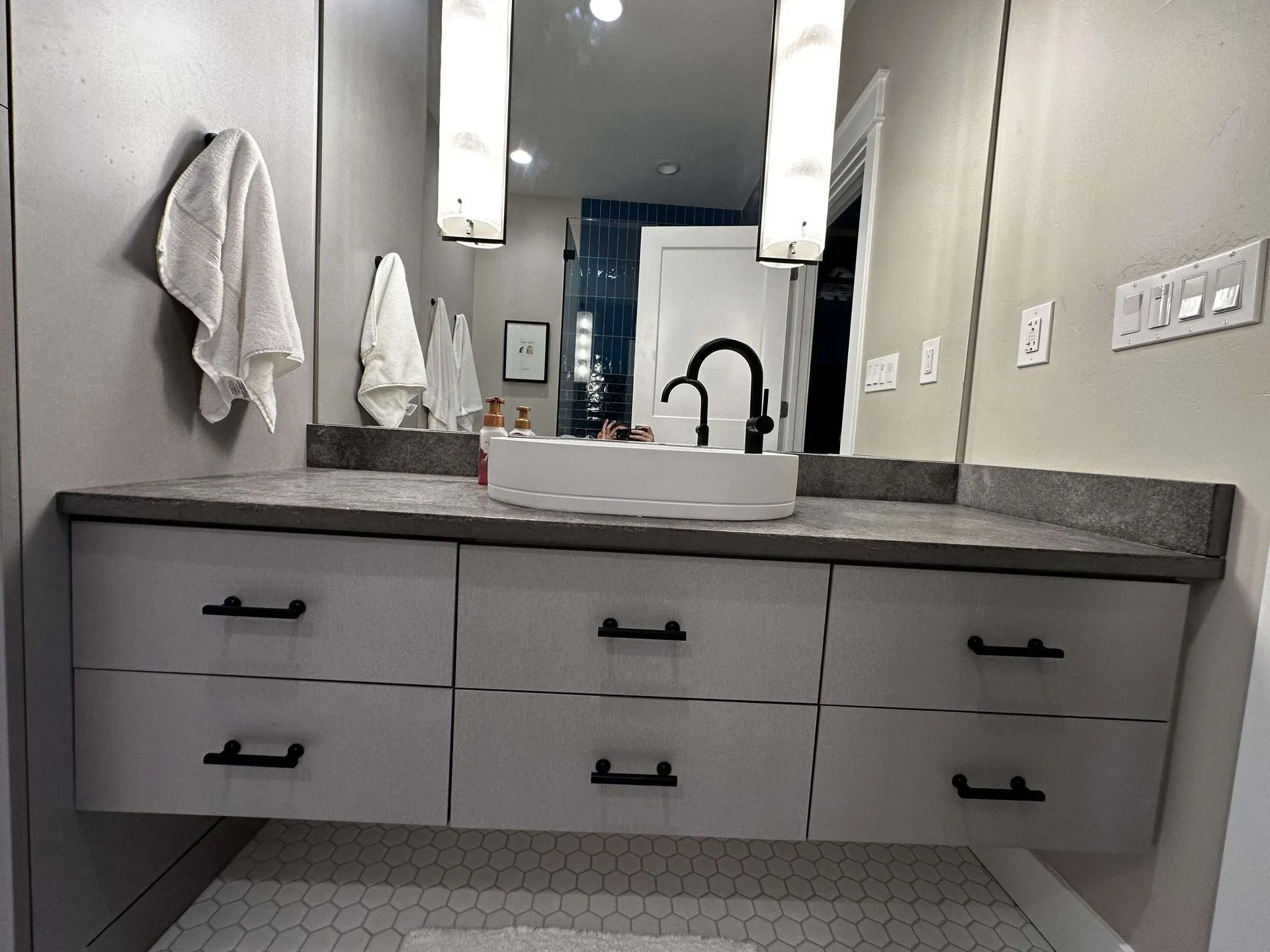Modern bathroom with floating vanity, gray countertop, black hardware, and large mirror.