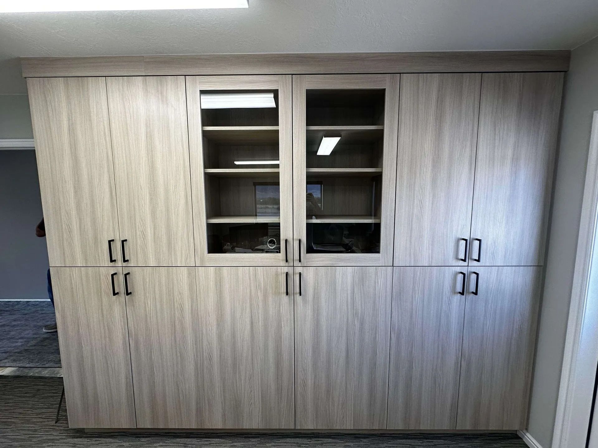 Built-in wooden cabinets with glass doors in the center and dark hardware.