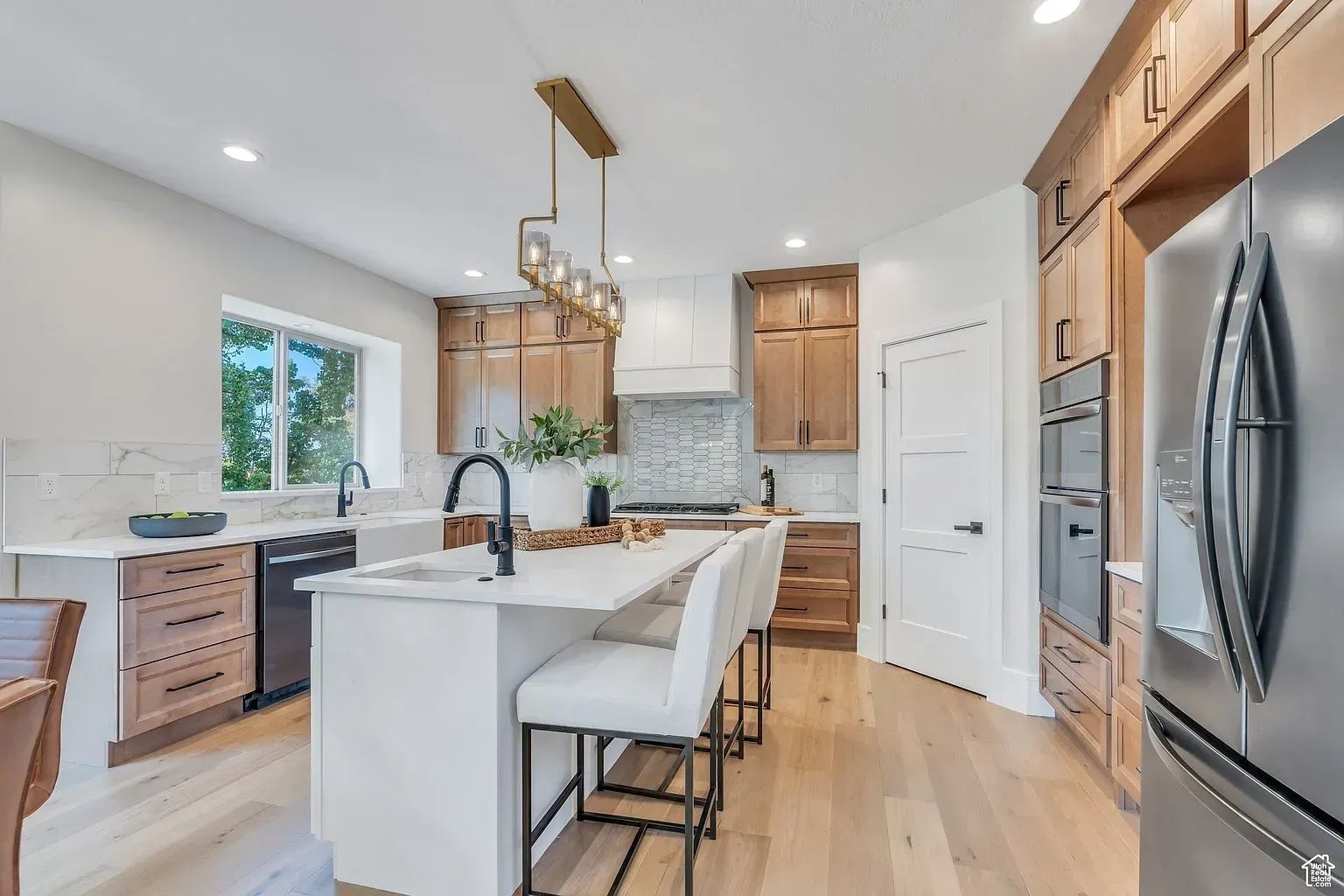 Modern kitchen with island, light wood cabinets, and stainless steel appliances.