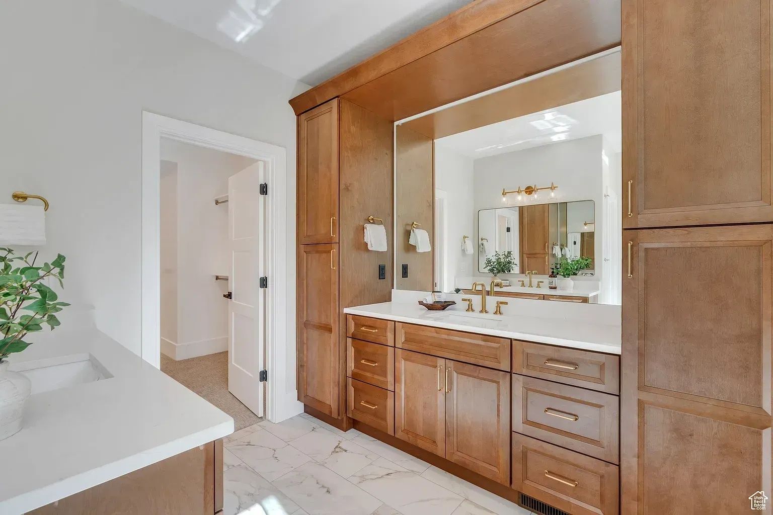 Bathroom with wooden cabinets, white countertops, and a large mirror.