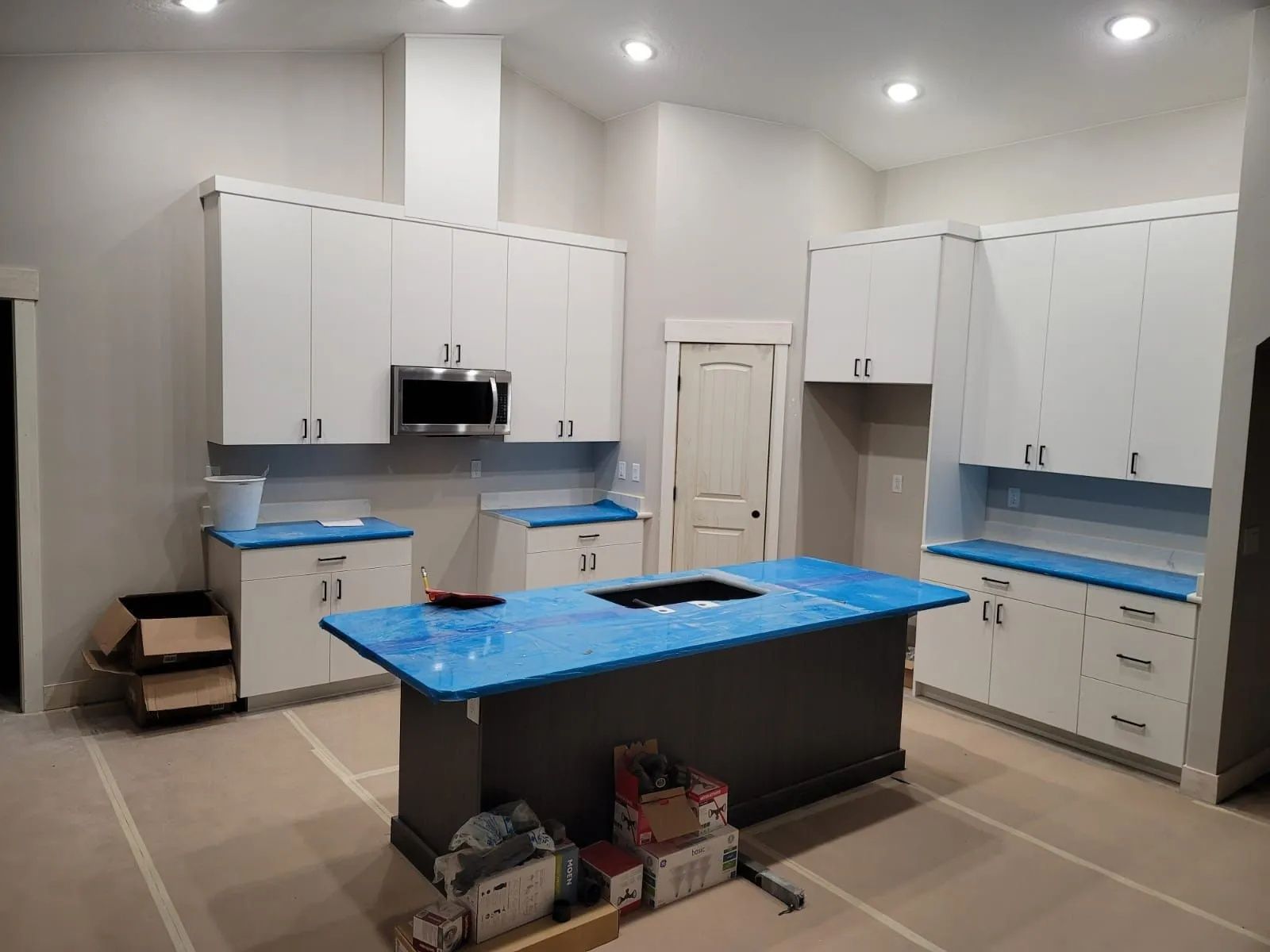 Newly installed kitchen with white cabinets, blue countertops, and dark gray island.