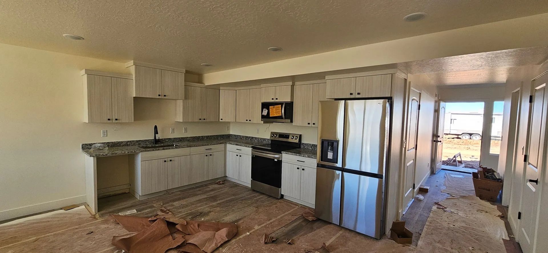 Kitchen with white cabinets, stainless steel appliances, and a hallway leading outside.