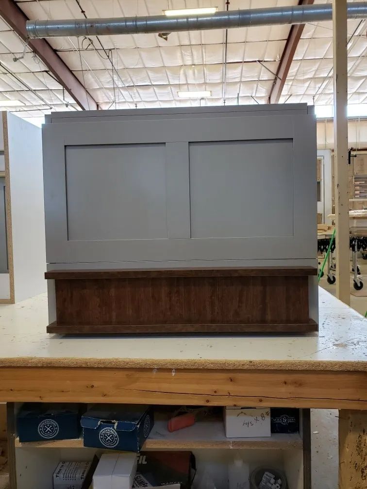 Gray and brown cabinet with two rectangular panels, sitting on a wooden surface.