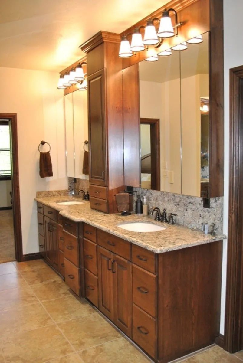 Bathroom with a long dark wood vanity, granite countertop, and large mirrors.
