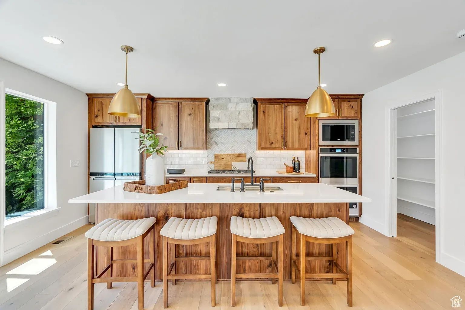 Modern kitchen with wooden cabinetry, island, and gold pendant lights.