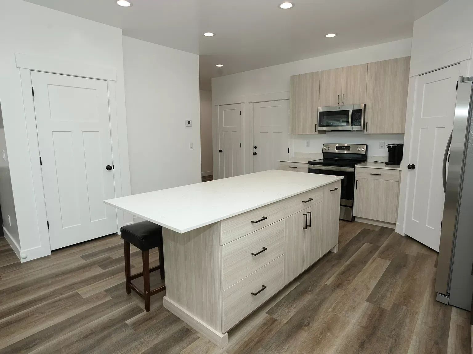 Modern kitchen with island, light wood cabinets, and stainless steel appliances.