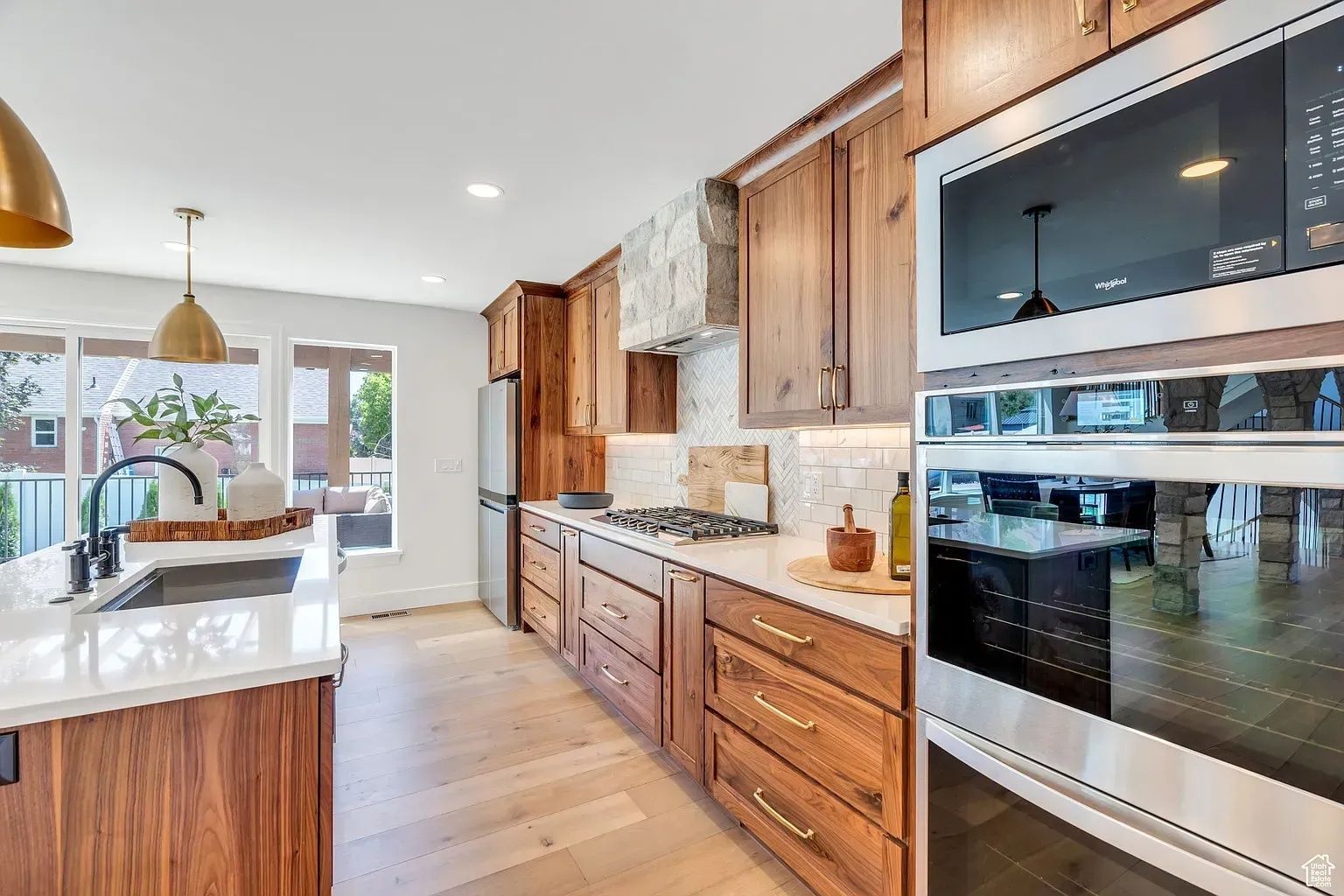 Modern kitchen with wood cabinets, stainless steel appliances, and white countertops.