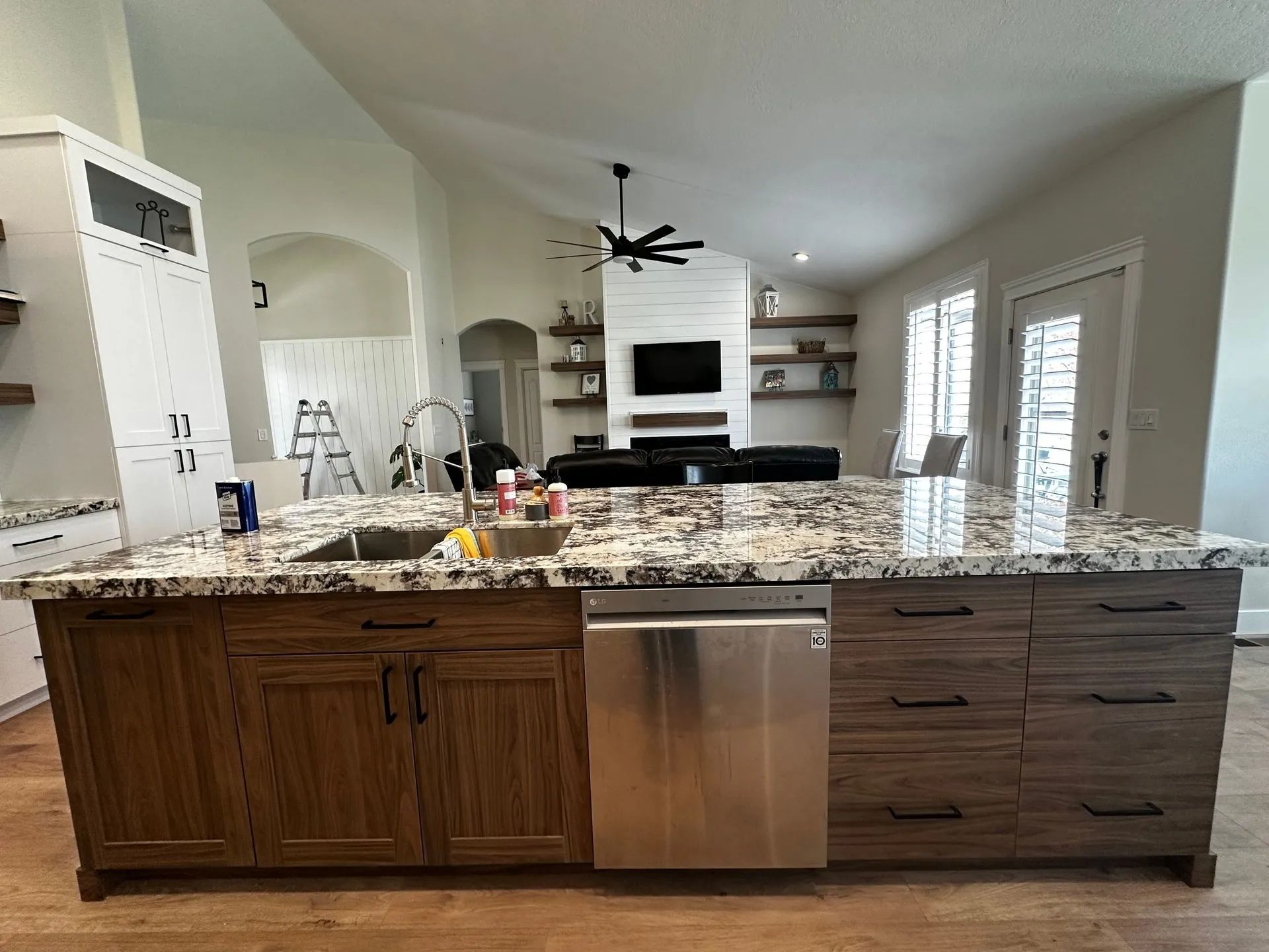 Kitchen island with granite countertop, wood cabinets, and a stainless steel dishwasher.