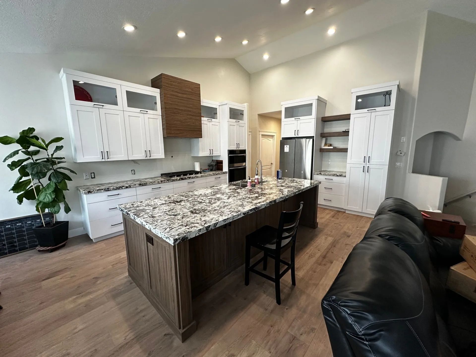 Spacious kitchen with a large island, white cabinets, and a wooden hood over the stove.