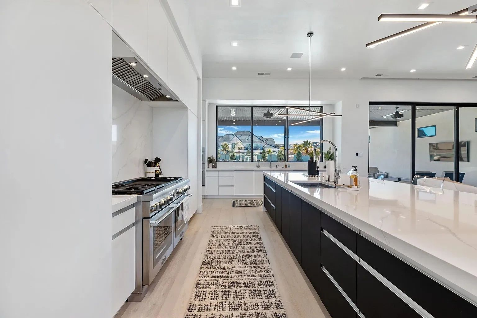 Modern kitchen with white countertops, black island, and large windows with mountain views.