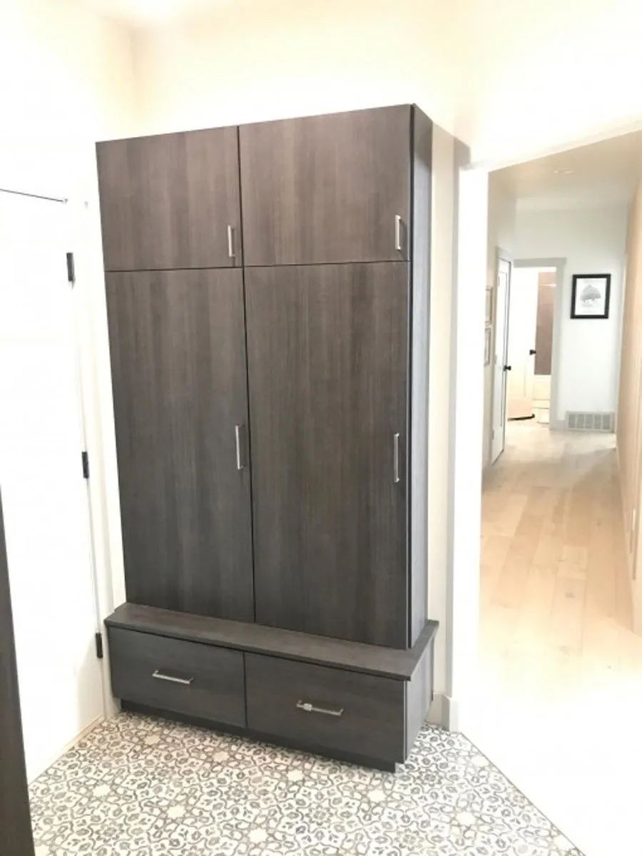 Dark gray cabinet with drawers and bench in a hallway, patterned floor.