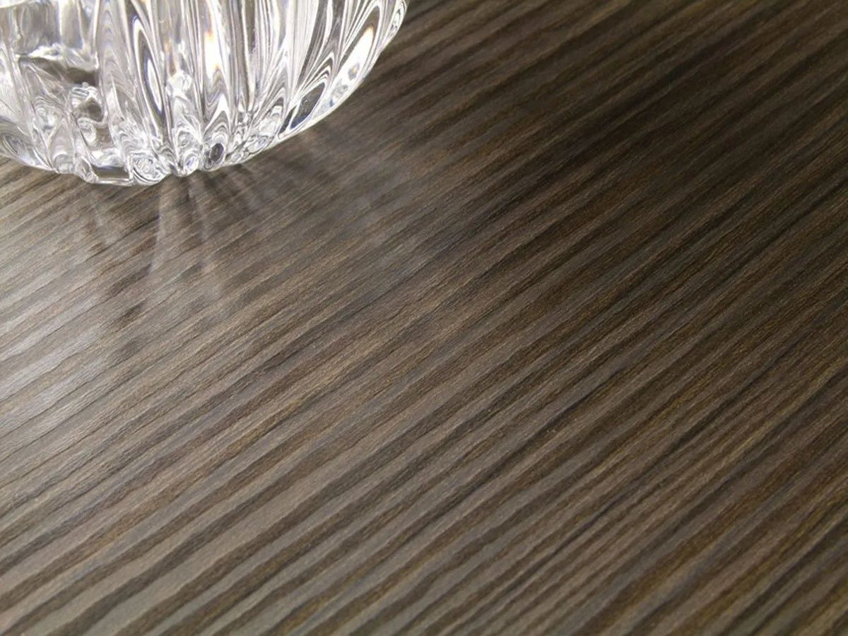 Crystal bowl on a textured, dark wooden surface, with light reflecting off the glass.