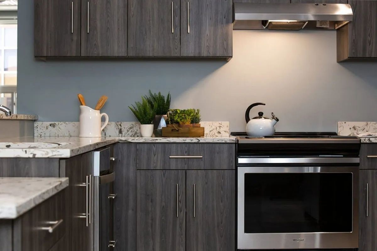 Gray kitchen cabinets and countertops with stainless steel oven and range hood.