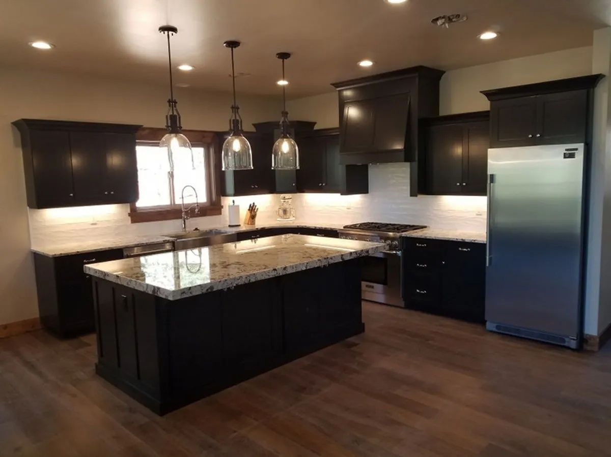 Kitchen with dark cabinets, granite countertops, island with pendant lights, stainless steel appliances.