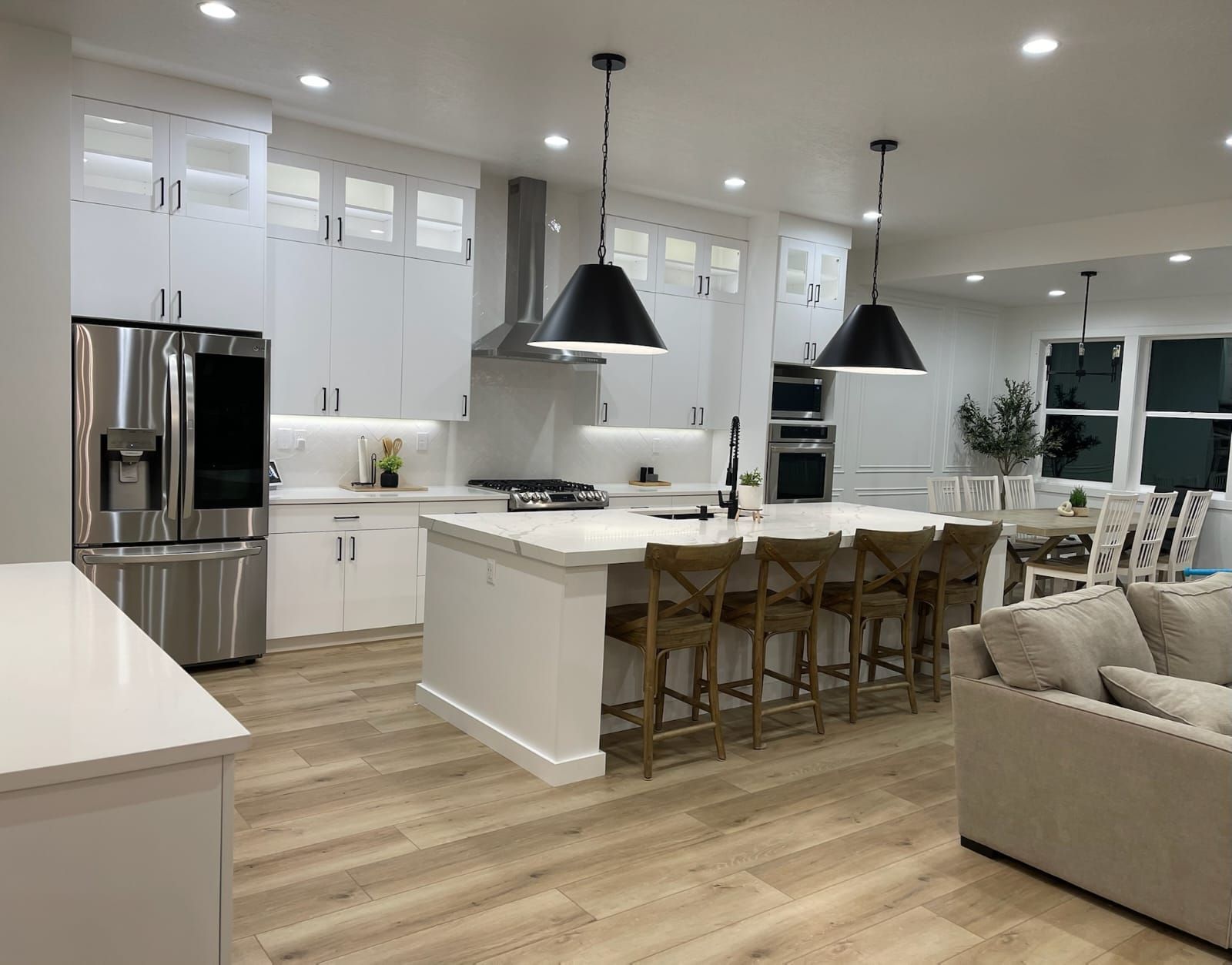 Modern kitchen with white cabinets, stainless steel appliances, and island with bar stools.