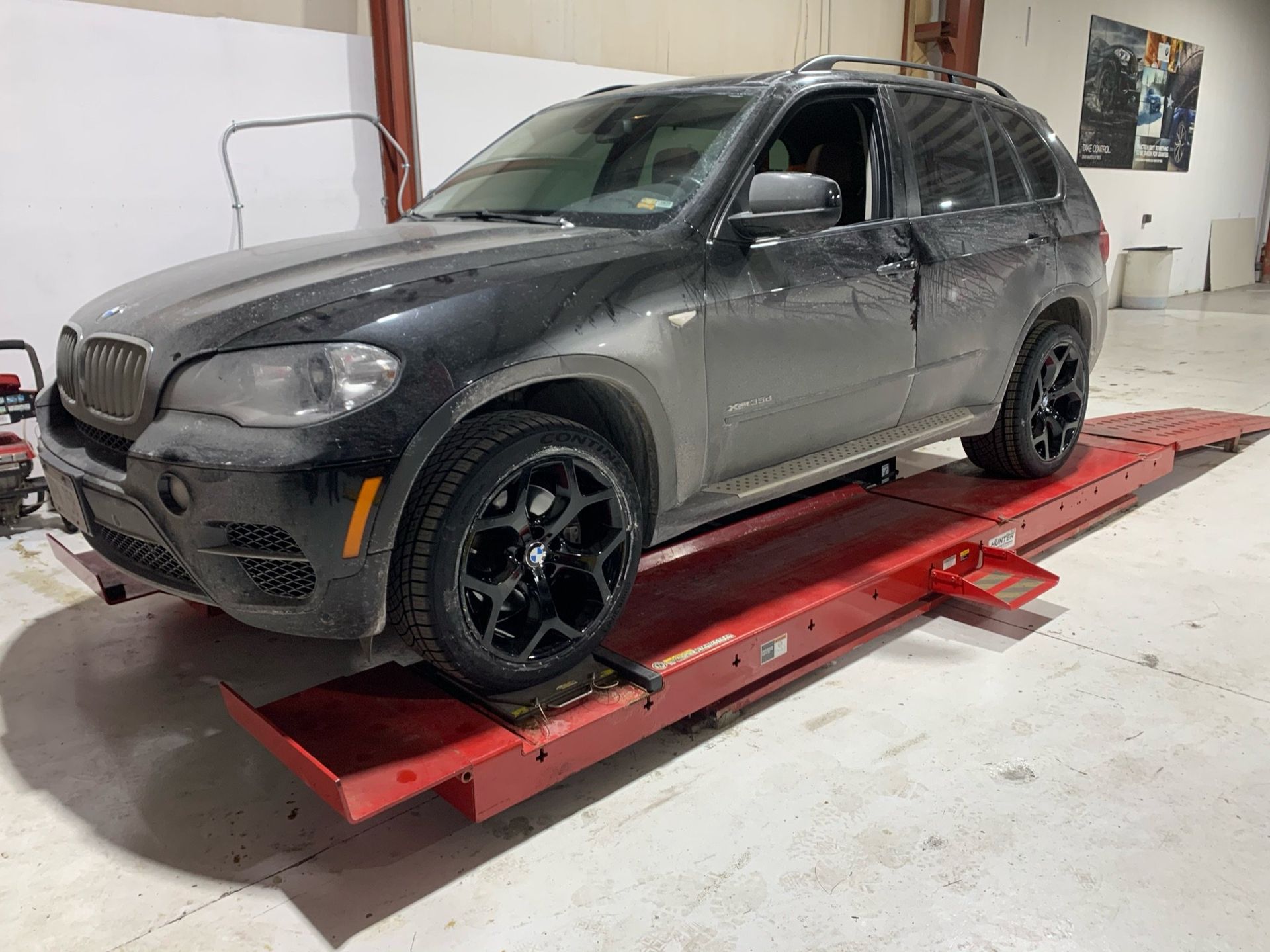 a black bmw x5 is sitting on top of a red ramp in a garage 