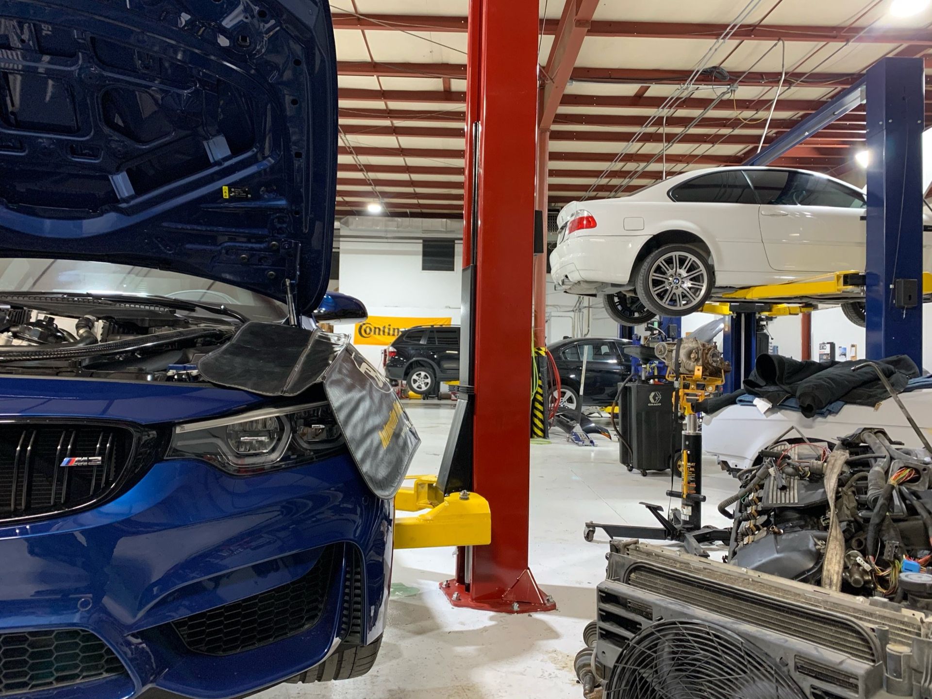 a blue car is parked next to a white car in a garage 