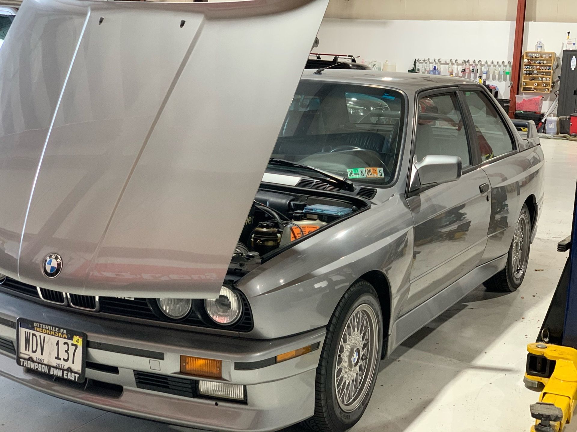 a silver bmw with the hood up is parked in a garage 