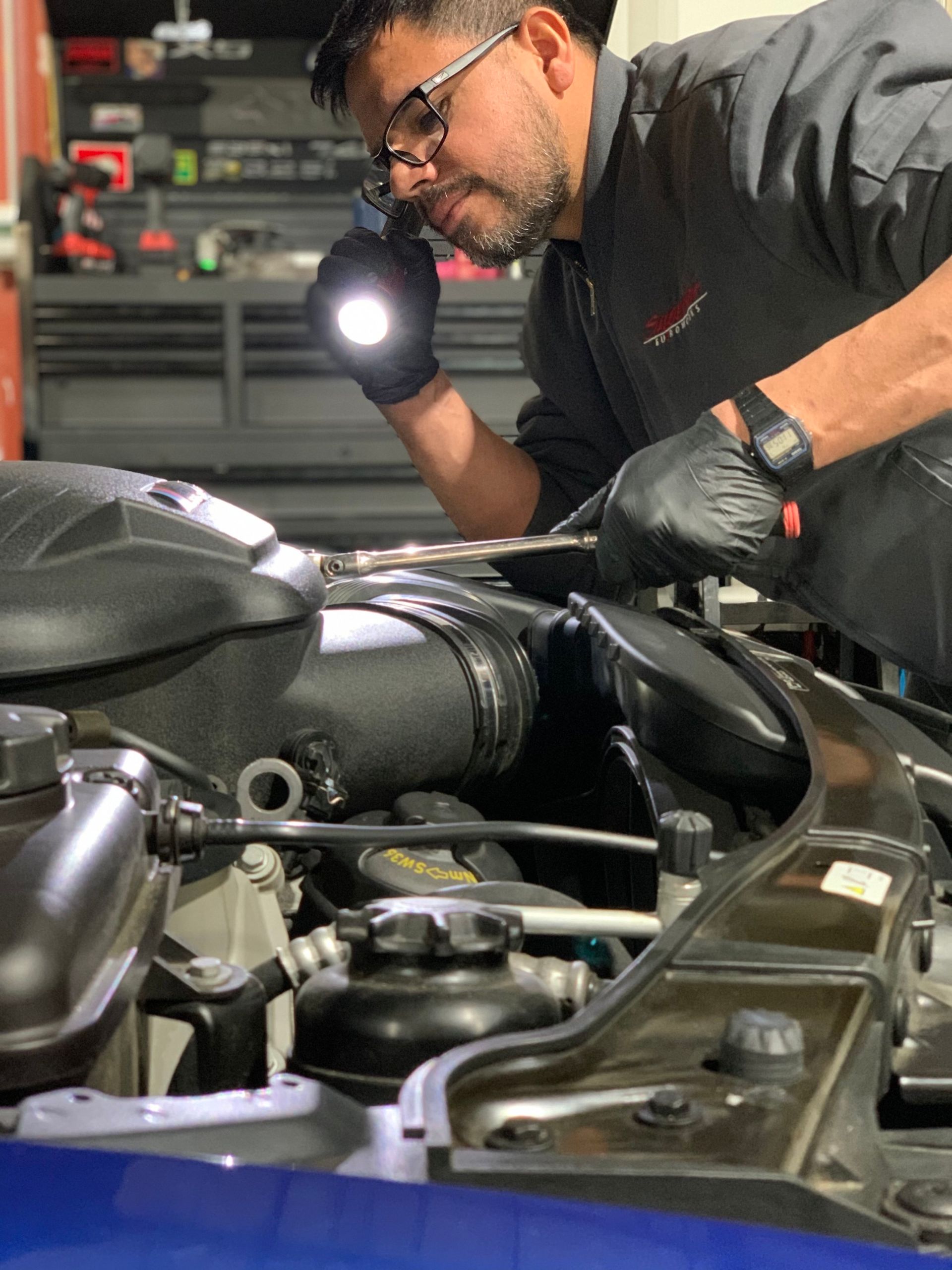 a man is working on the engine of a car with a flashlight