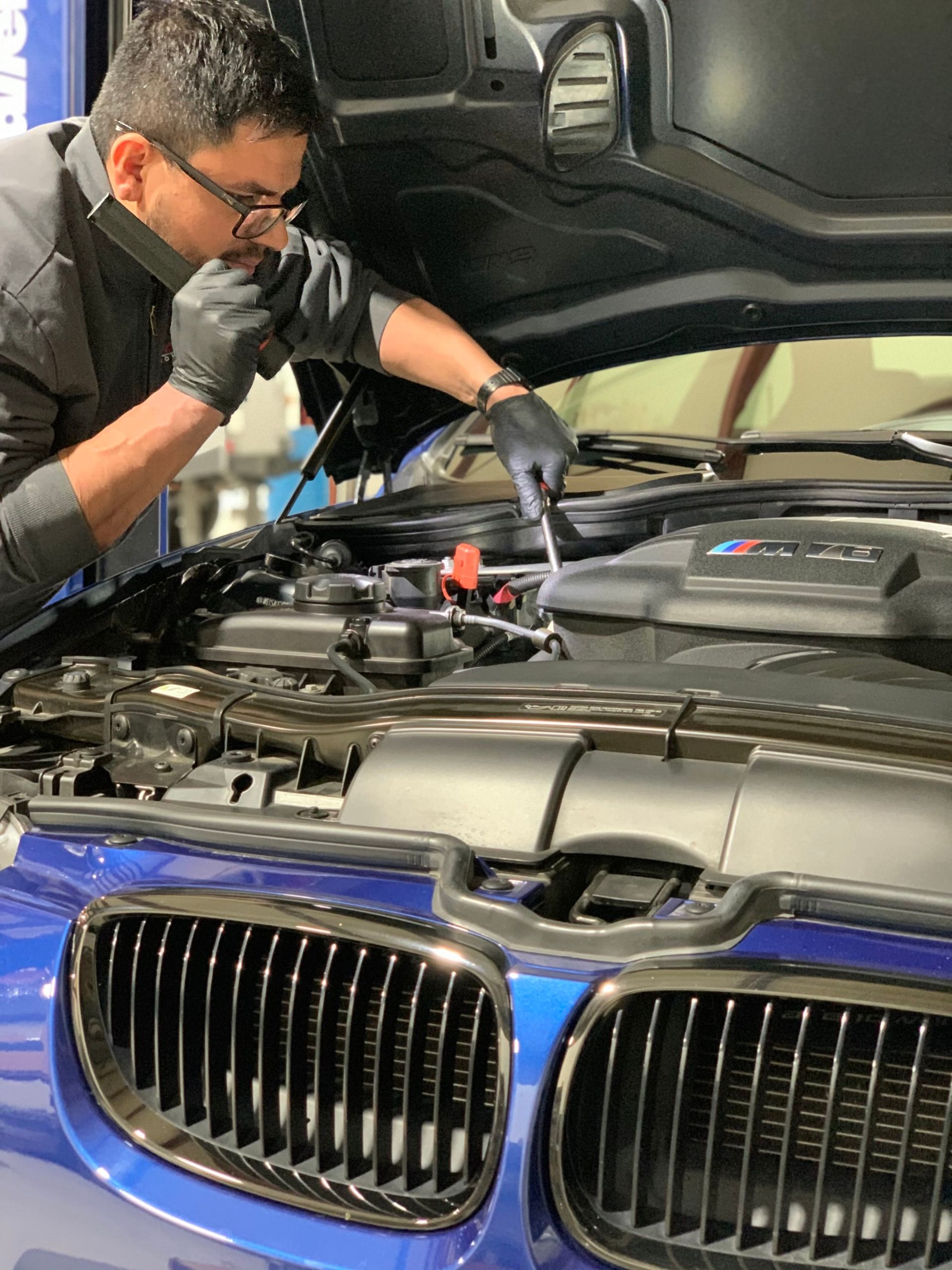 a man is working on the engine of a blue bmw