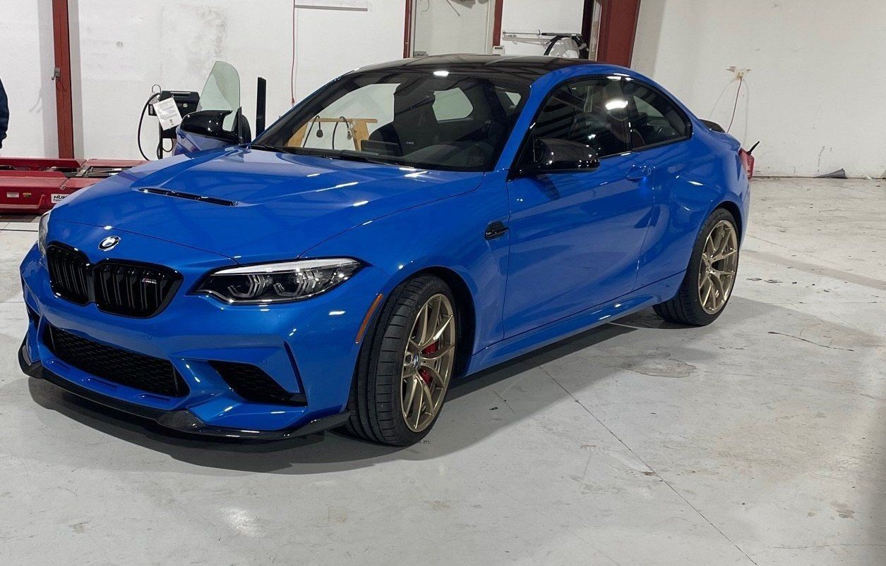 a blue bmw m2 is parked in a garage