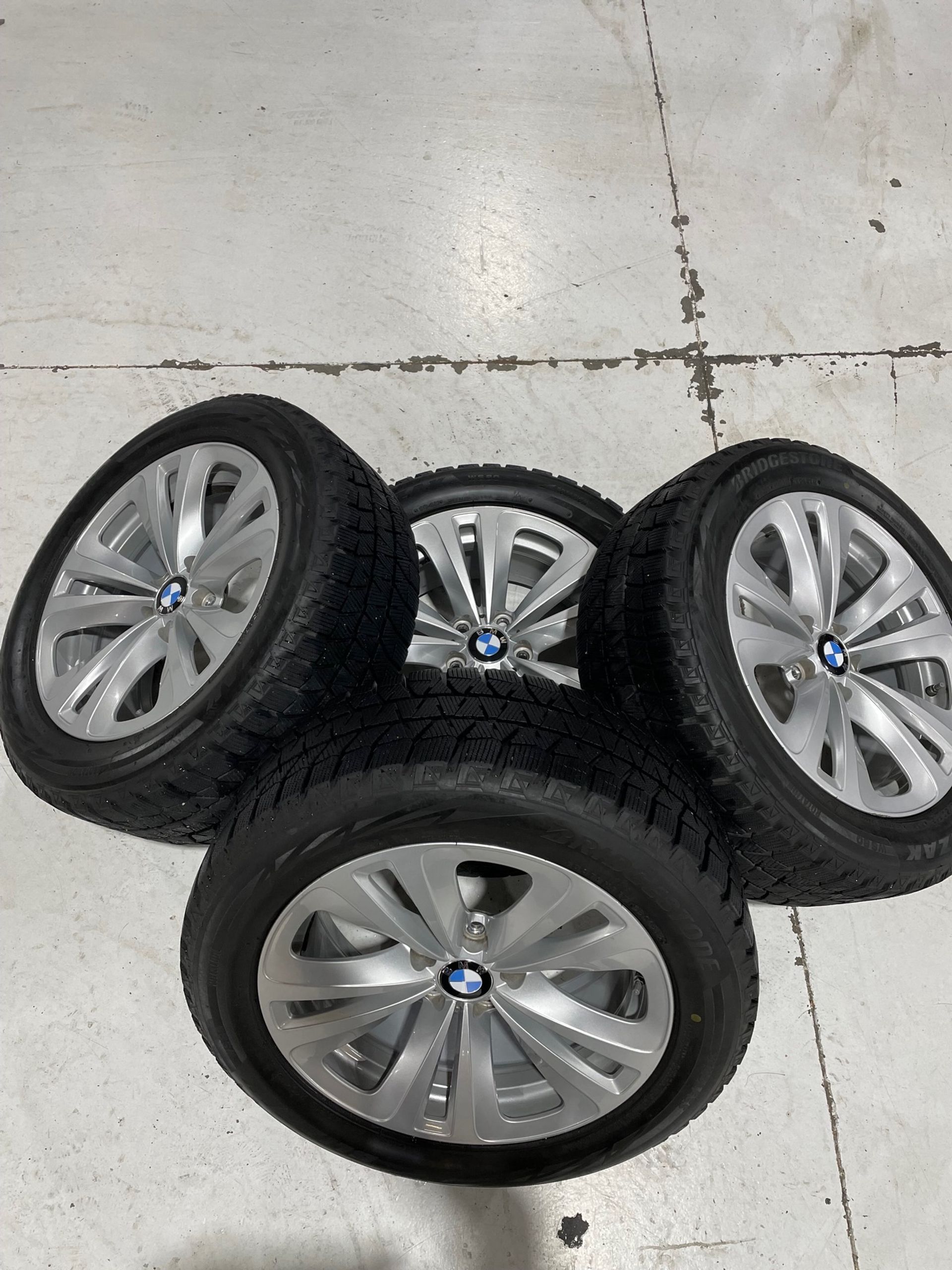four bmw wheels and tires are stacked on top of each other on a white floor