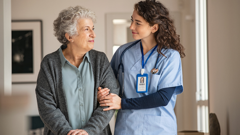 A nurse is holding the hand of an elderly woman.