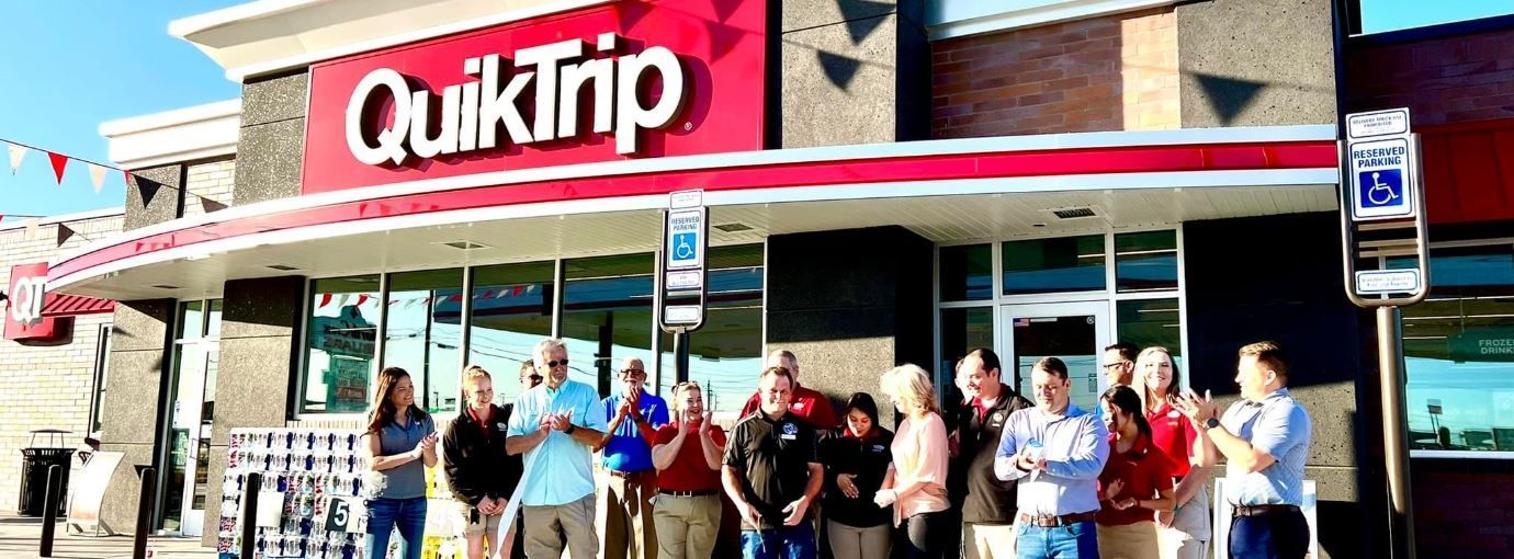 A group of people are standing in front of a quiktrip gas station.