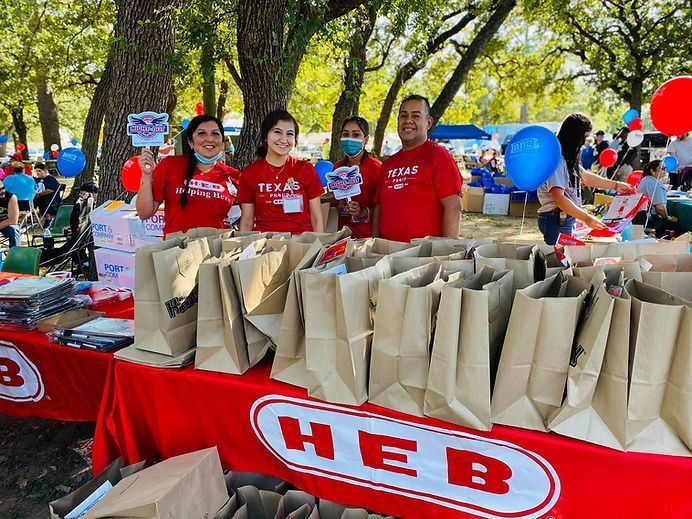 A group of people are standing around a table filled with bags and balloons.