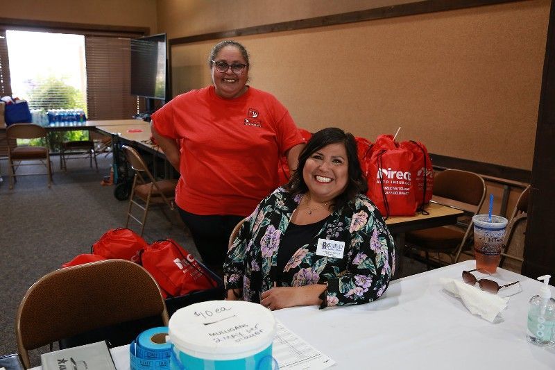 Two women are standing next to each other at a table.