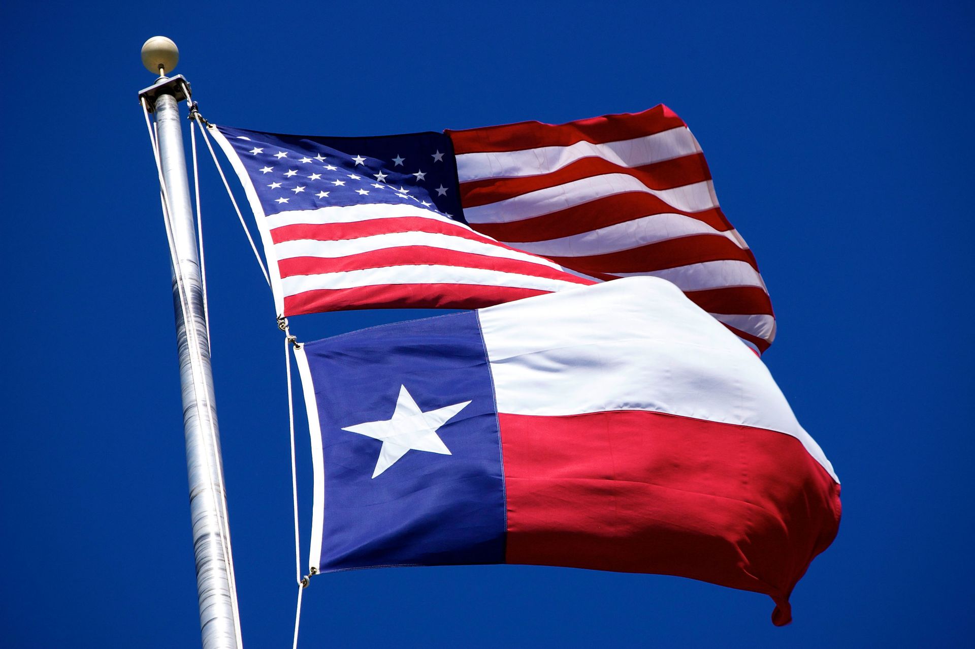 An american flag and a texas flag waving in the wind