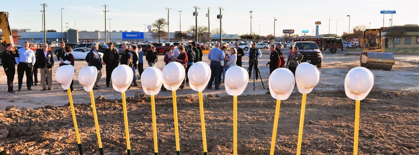 A group of people are standing in front of a row of shovels.