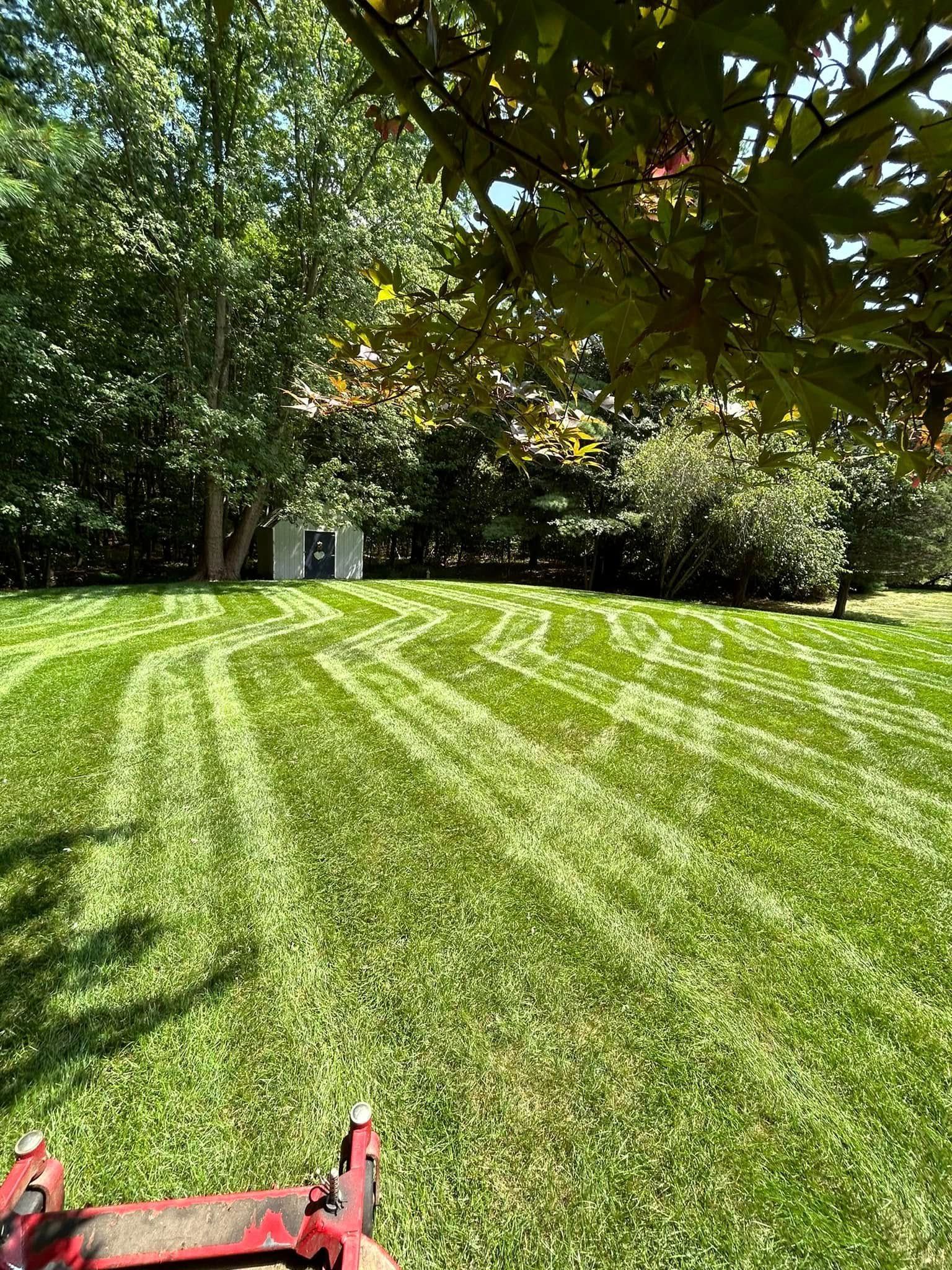 A person is mowing a lush green lawn with a lawn mower.