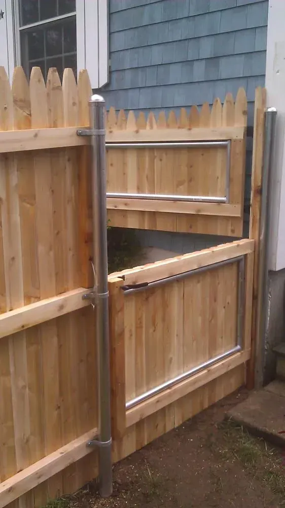 Wooden fence with a gate, leaning, outside a blue house.
