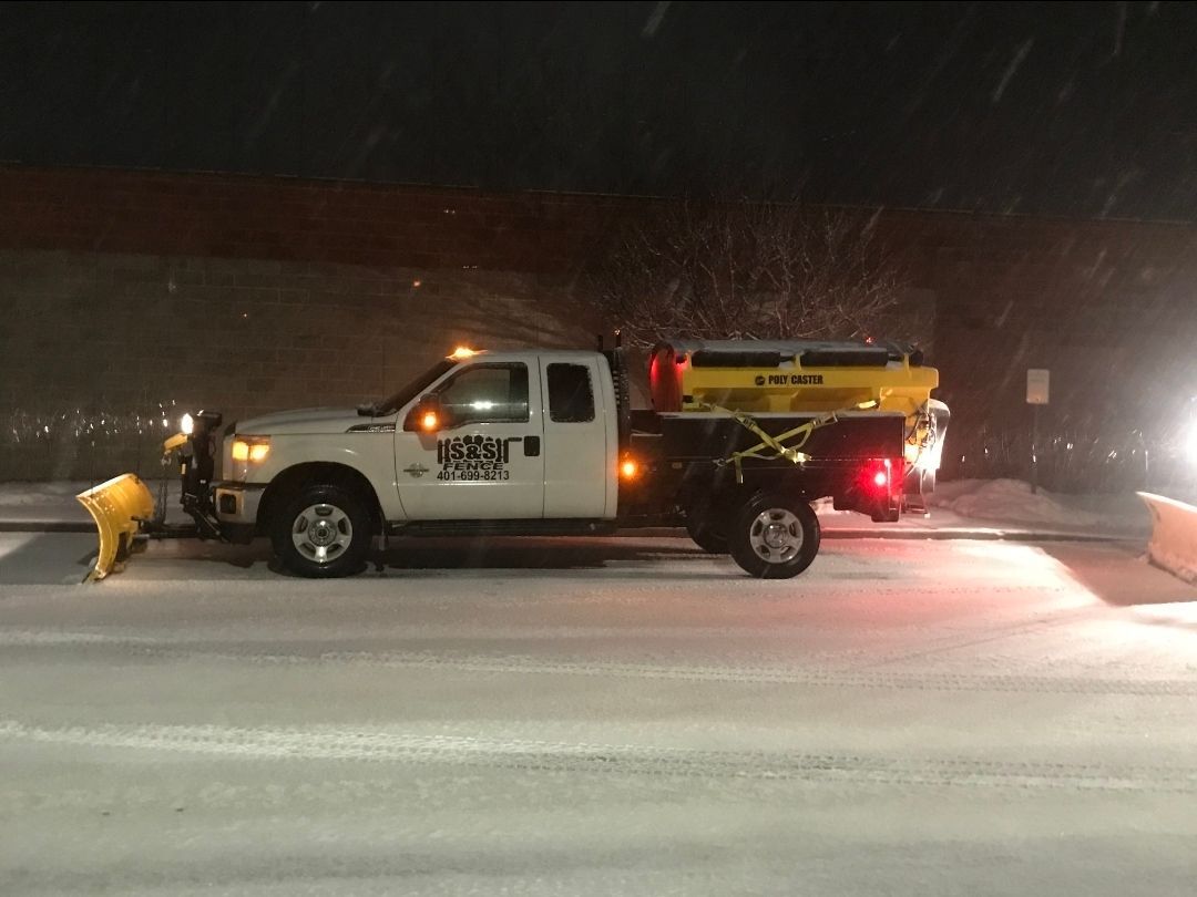 Tow truck with flashing lights clearing a snow-covered road at night