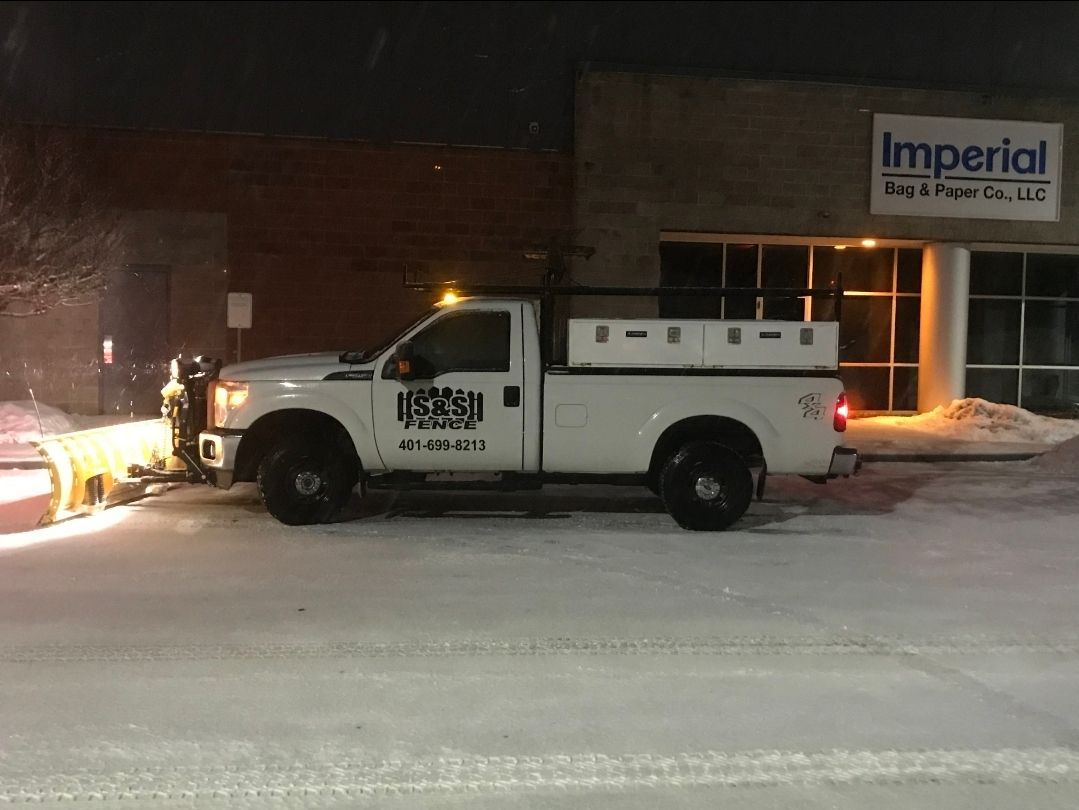 White pickup truck parked beside a building at night with snow on the ground and a lit sign reading “Imperial”