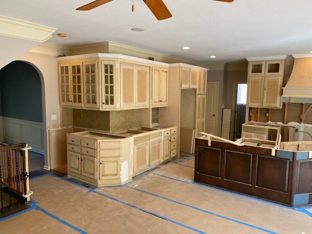 A kitchen is being remodeled with wooden cabinets and a ceiling fan.