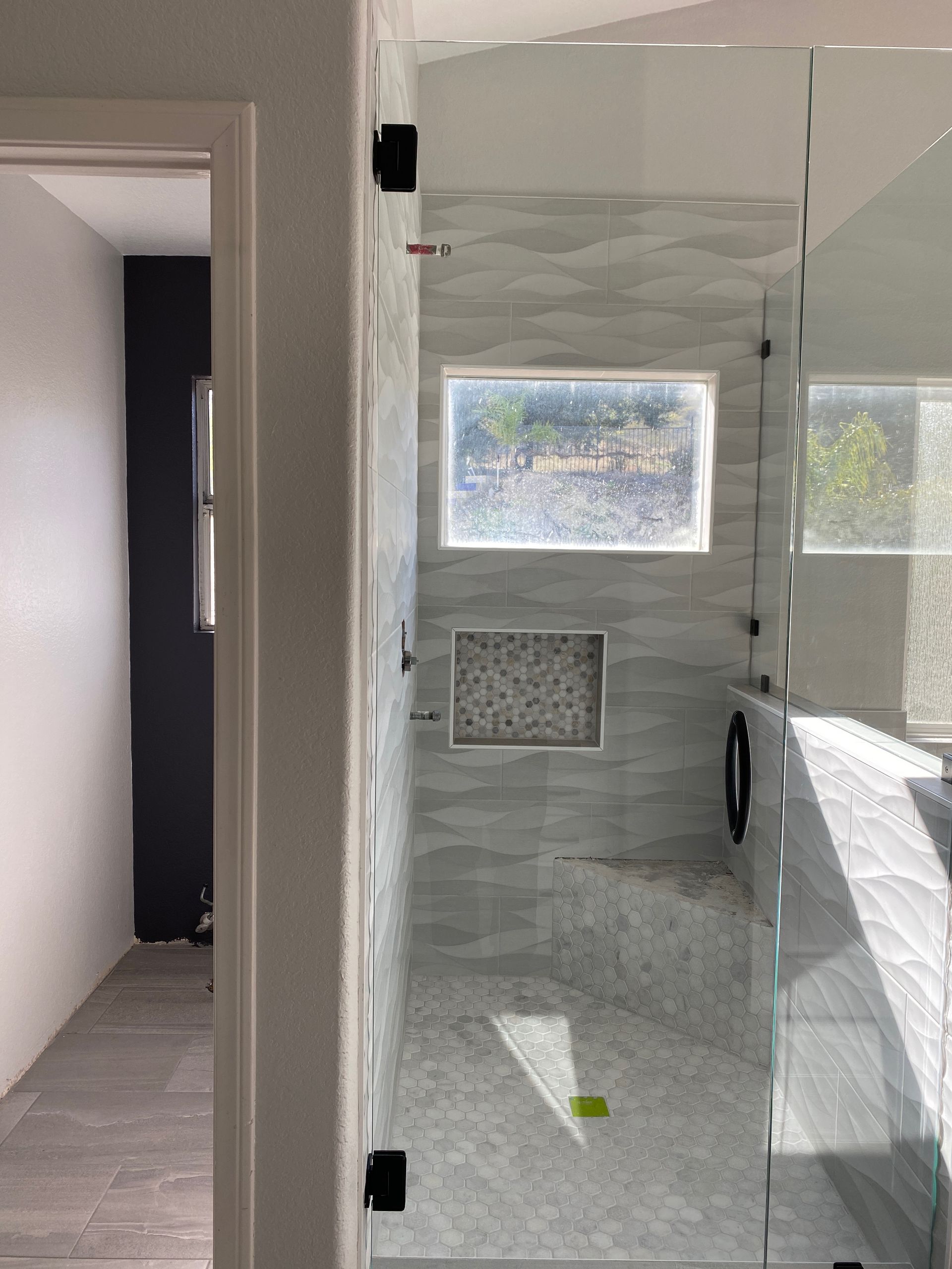 A bathroom with a walk in shower and a window.