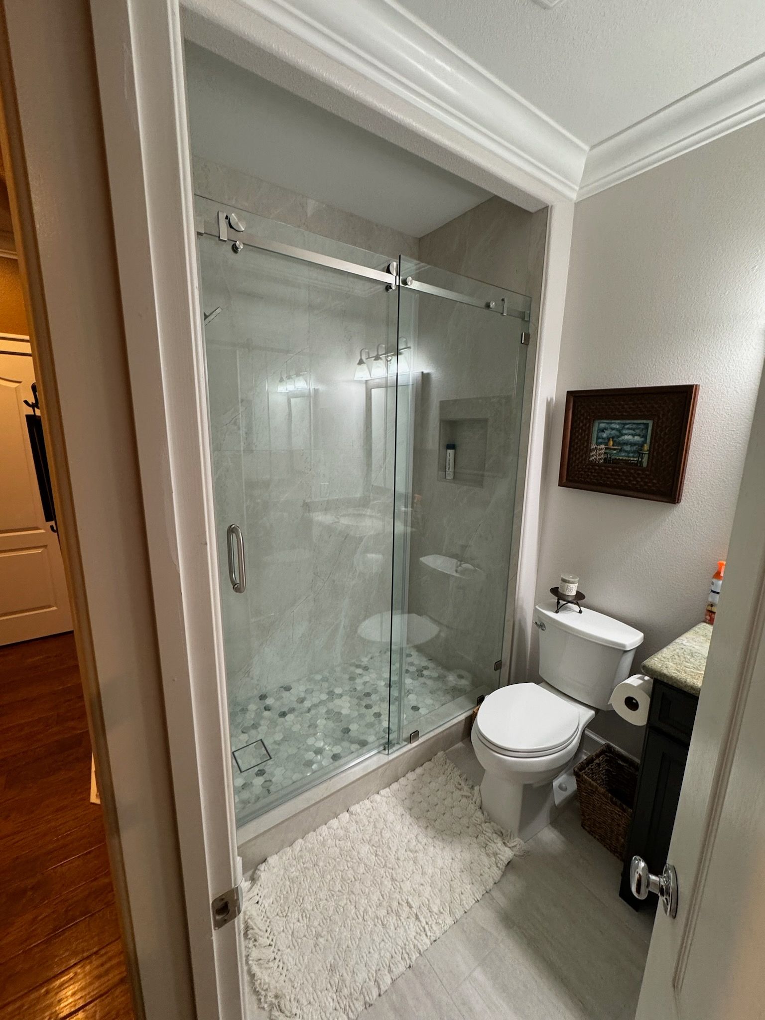 A bathroom with a toilet , sink , shower and glass door.